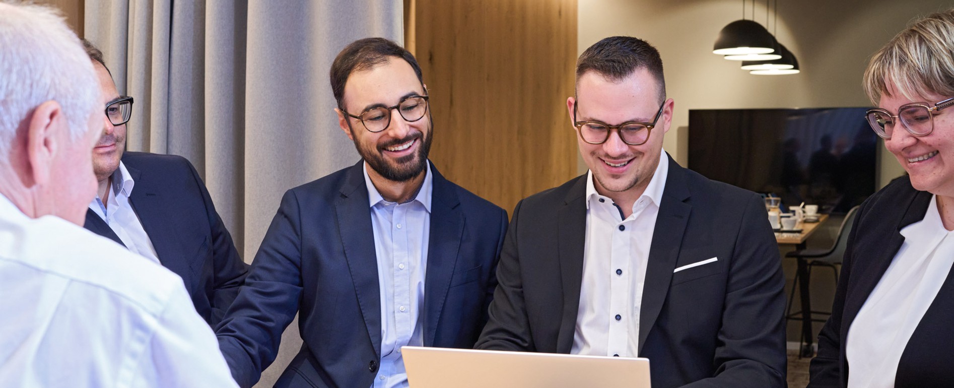 Berater und Beraterinnen der Bank schauen gemeinsam auf ein Laptop